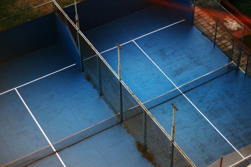 Padel tereni snimljeni odozgo, plava veštačka trava unutar staklenih zidova i ograde